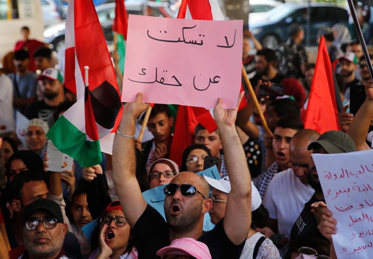 A Palestinian protester shouts slogans as he holds up an Arabic placard that reads: "Don't be silent when it comes to your rights"