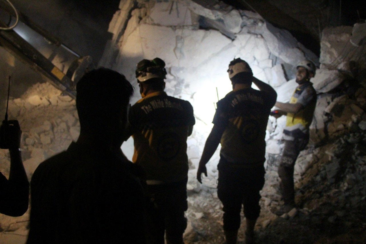 Syria Civil Defence (White Helmets) members search the rubble of a damaged building for victims
