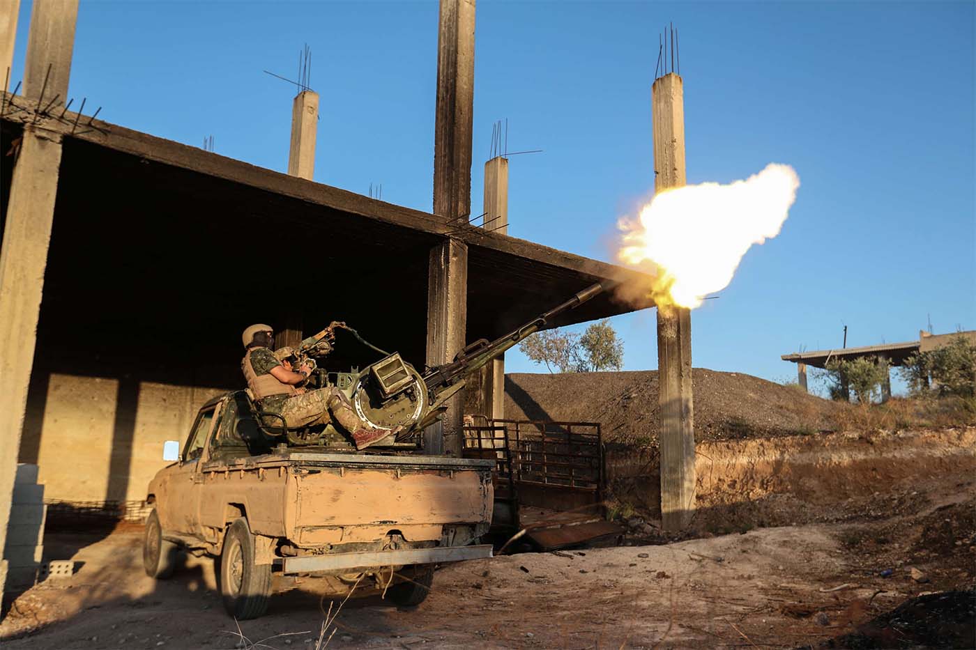 A fighter from the former al-Qaeda Syrian affiliate Hayat Tahrir al-Sham (HTS) fires an anti-aircraft gun mounted on a pickup truck in Syria's southern Idlib province 