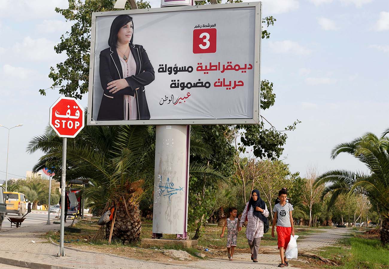 People walk past an election campaign billboard depicting presidential candidate, Abir Moussi, in Tunis