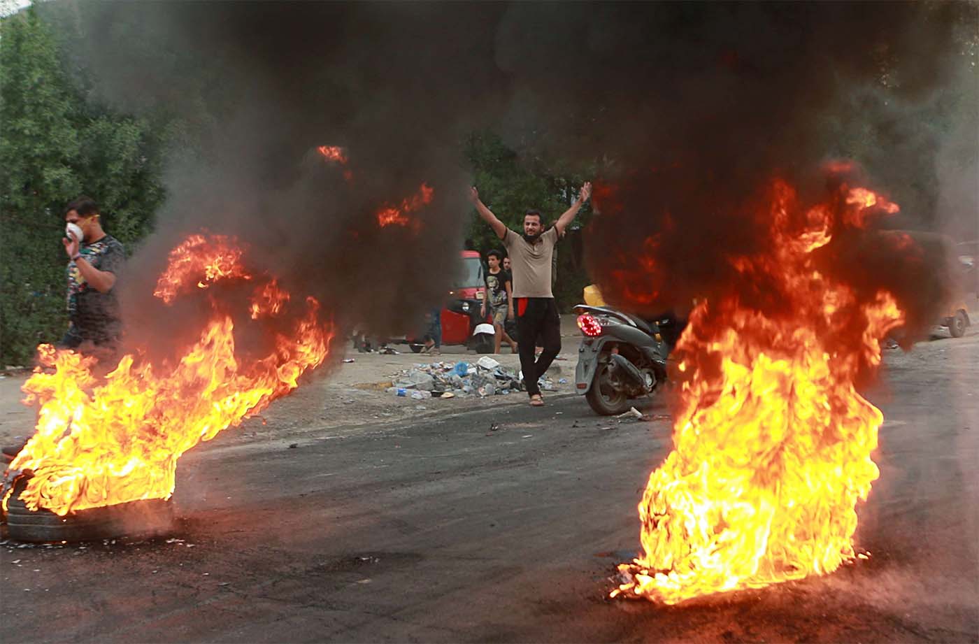 Anti-government protesters set fires and close a street during a demonstration in Baghdad