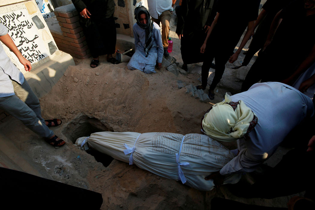 Iraqi men bury a demonstrator, who was killed during anti-government protests, at the cemetery in Najaf