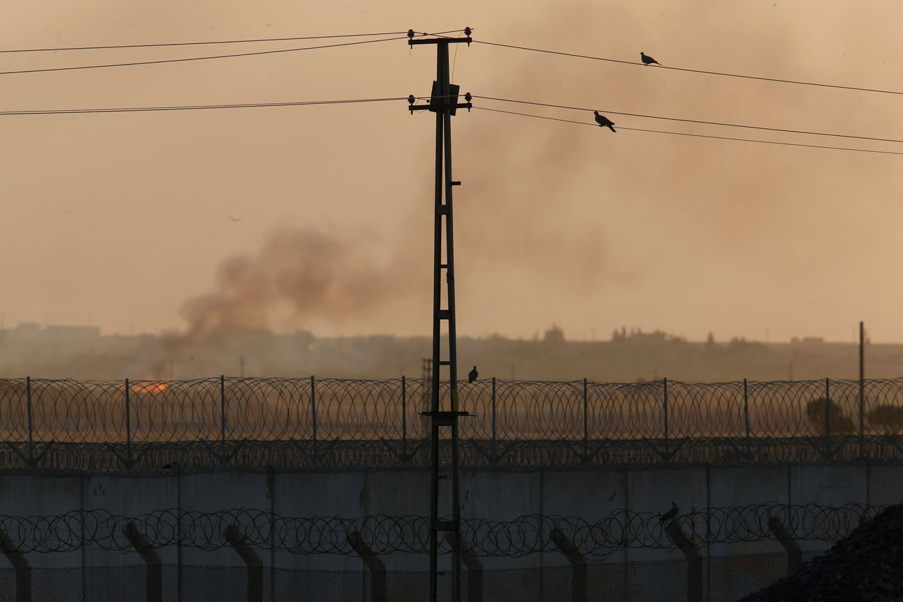 Barbed wire and smoke seen in a photo taken from the Turkish side of the border between Turkey and Syria