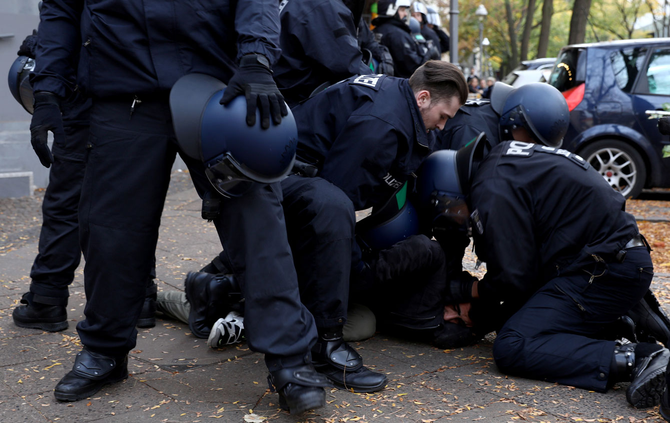 Police officers detain a man as Kurds demonstrate against Turkey's military action in northeastern Syria in Berlin