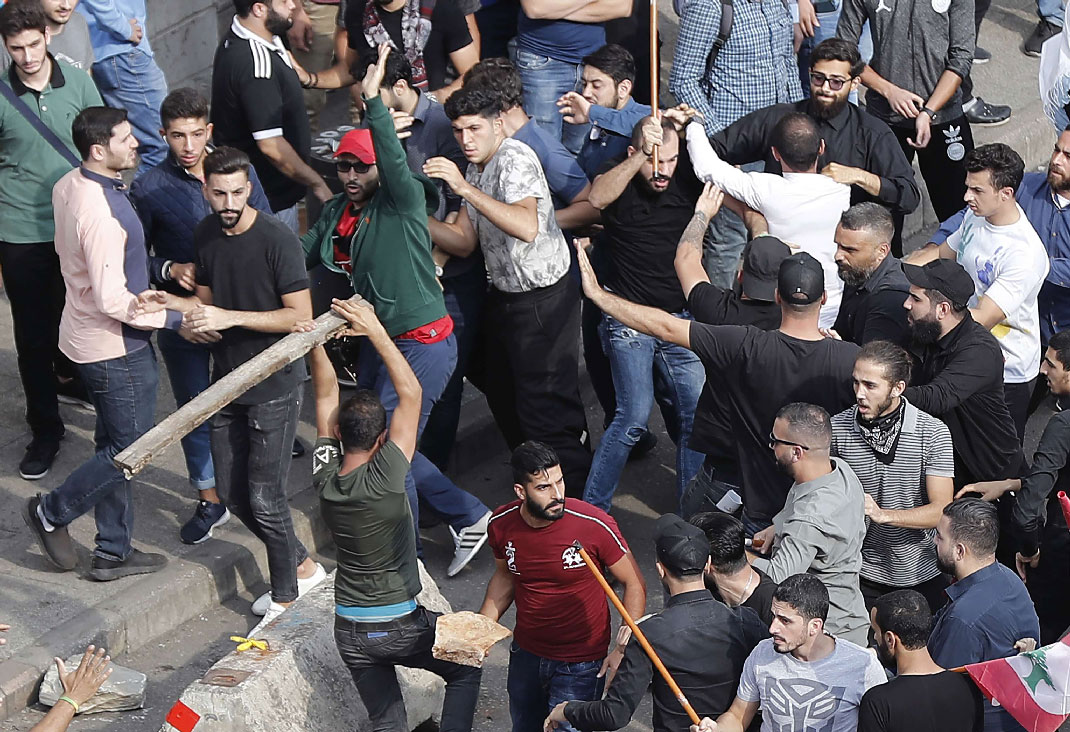 Anti-government protesters and Hezbollah supporters clash during a protest near the government palace, in downtown Beirut