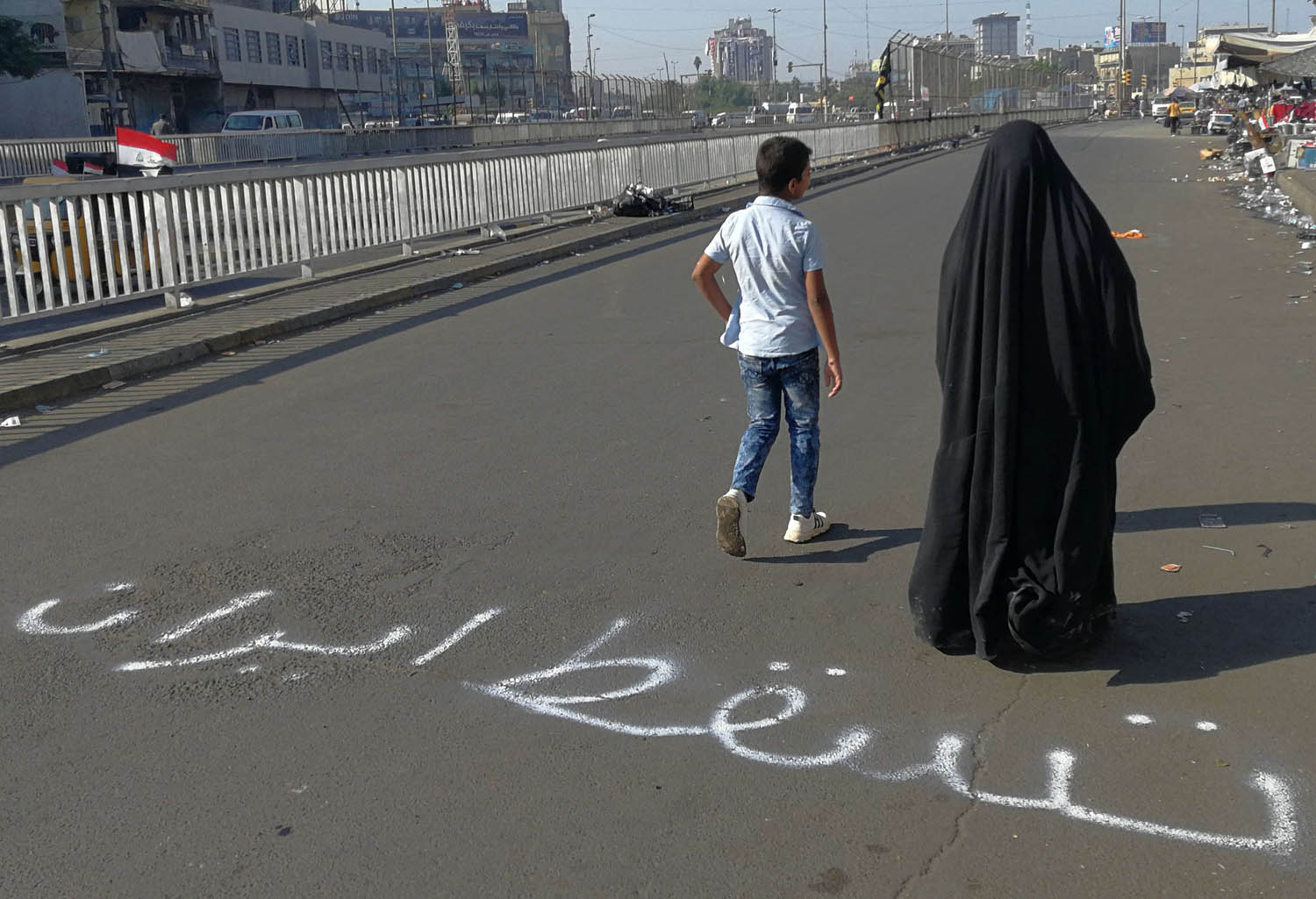أم عراقية وابنها يمران في منطقة الاعتصامات في بغداد