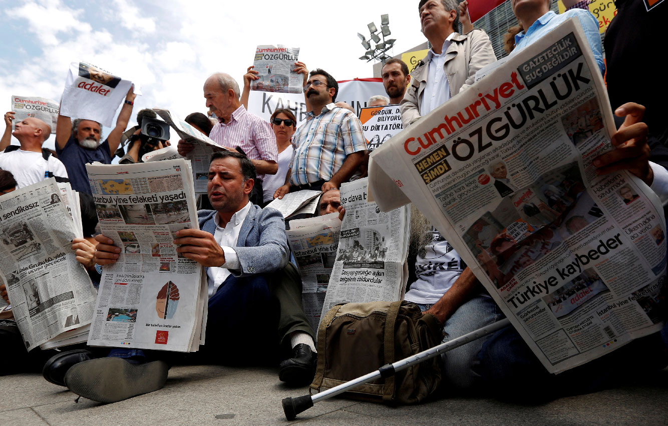 Press freedom activists read opposition newspaper Cumhuriyet during a demonstration