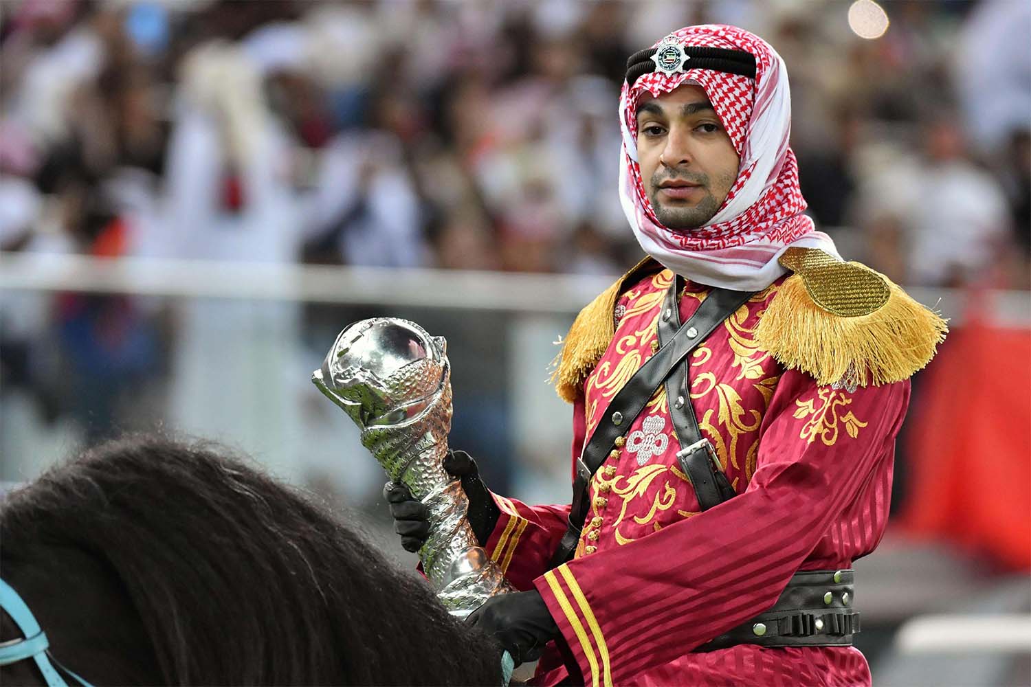A mounted policeman wearing a traditional outfit arrives with the trophy prior to the Gulf Cup of Nations 2017 final football match 