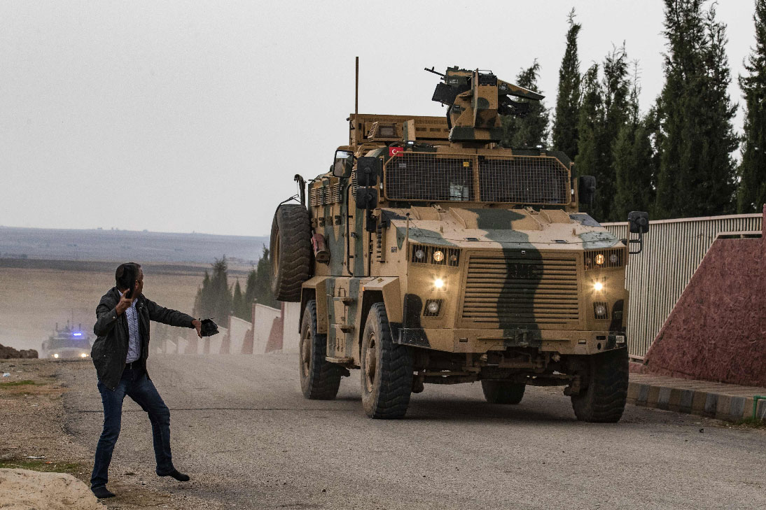  A man tosses his shoes at a Turkish military vehicle on patrol in the countryside of the town of Darbasiyah