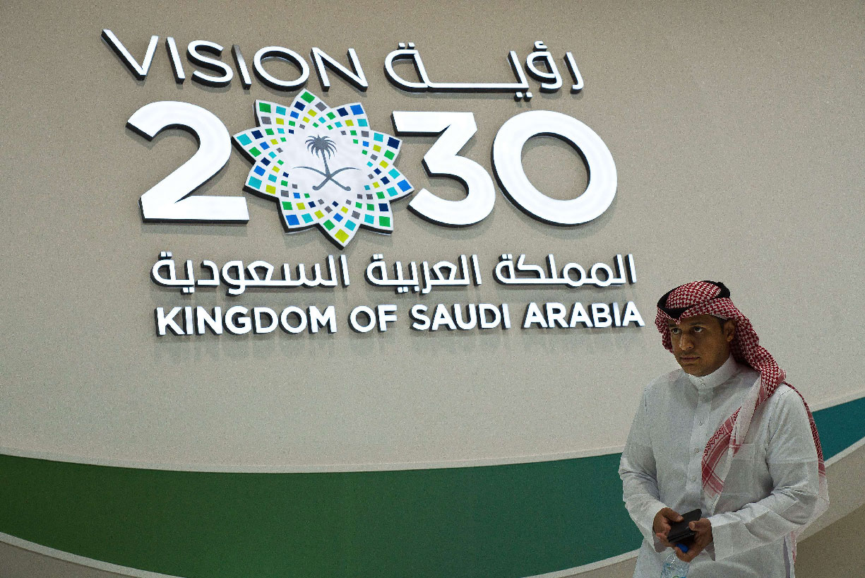 A Saudi man walks past a "Vision 2030" display
