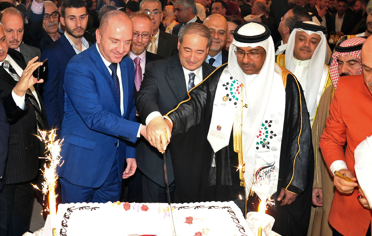 United Arab Emirates Charge d'affaires Abdul-Hakim Naimi, center right, cuts a cake with Syria's Deputy Foreign Minister Faisal Mekdad
