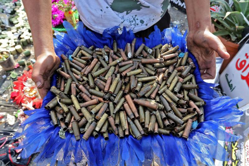 An Iraqi anti-government demonstrator shows a basket full of empty bullet cartridges found in Baghdad’s Tahrir Square