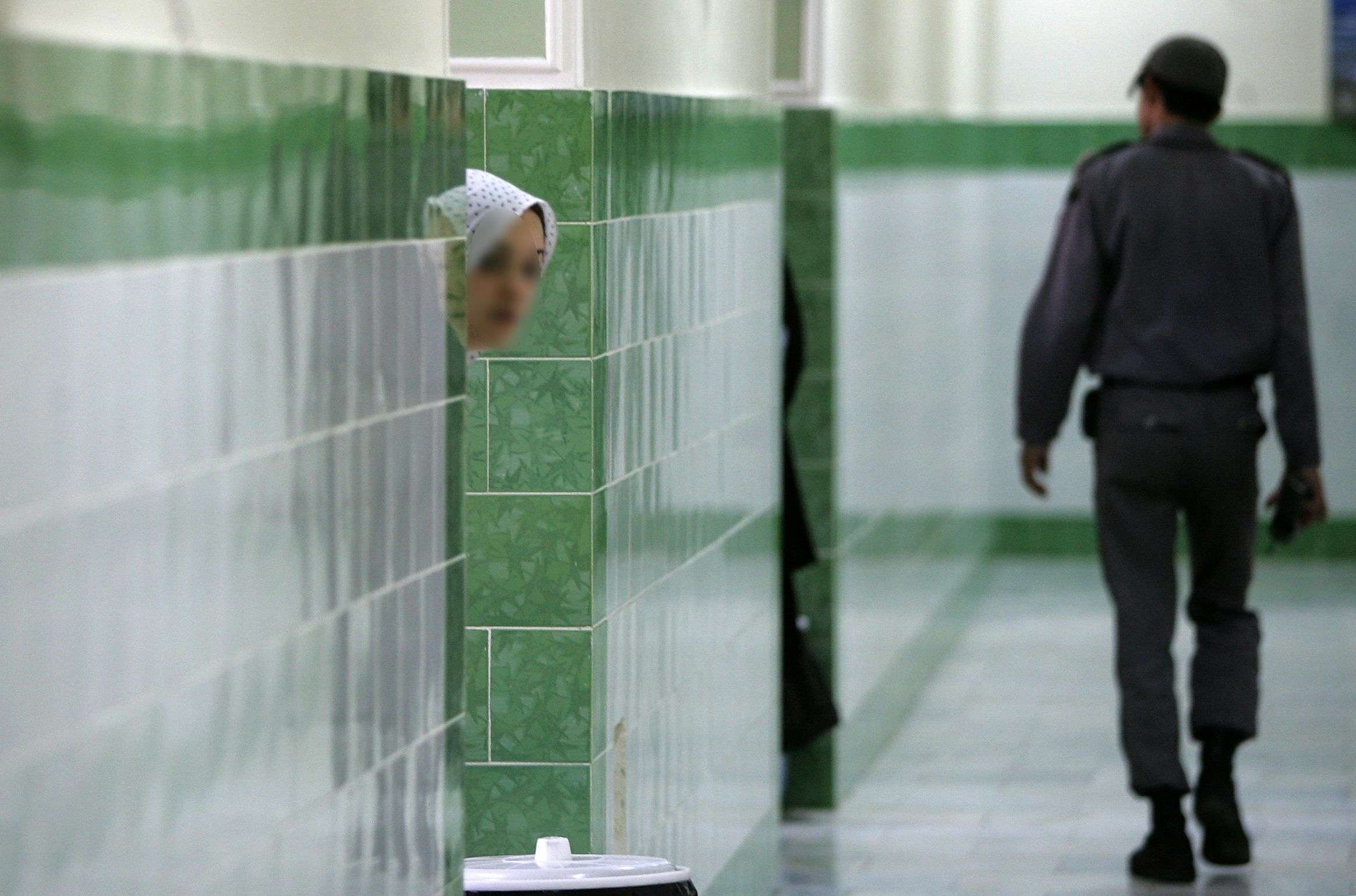 An Iranian inmate peers from behind a wall at the infamous Evin prison north of Tehran