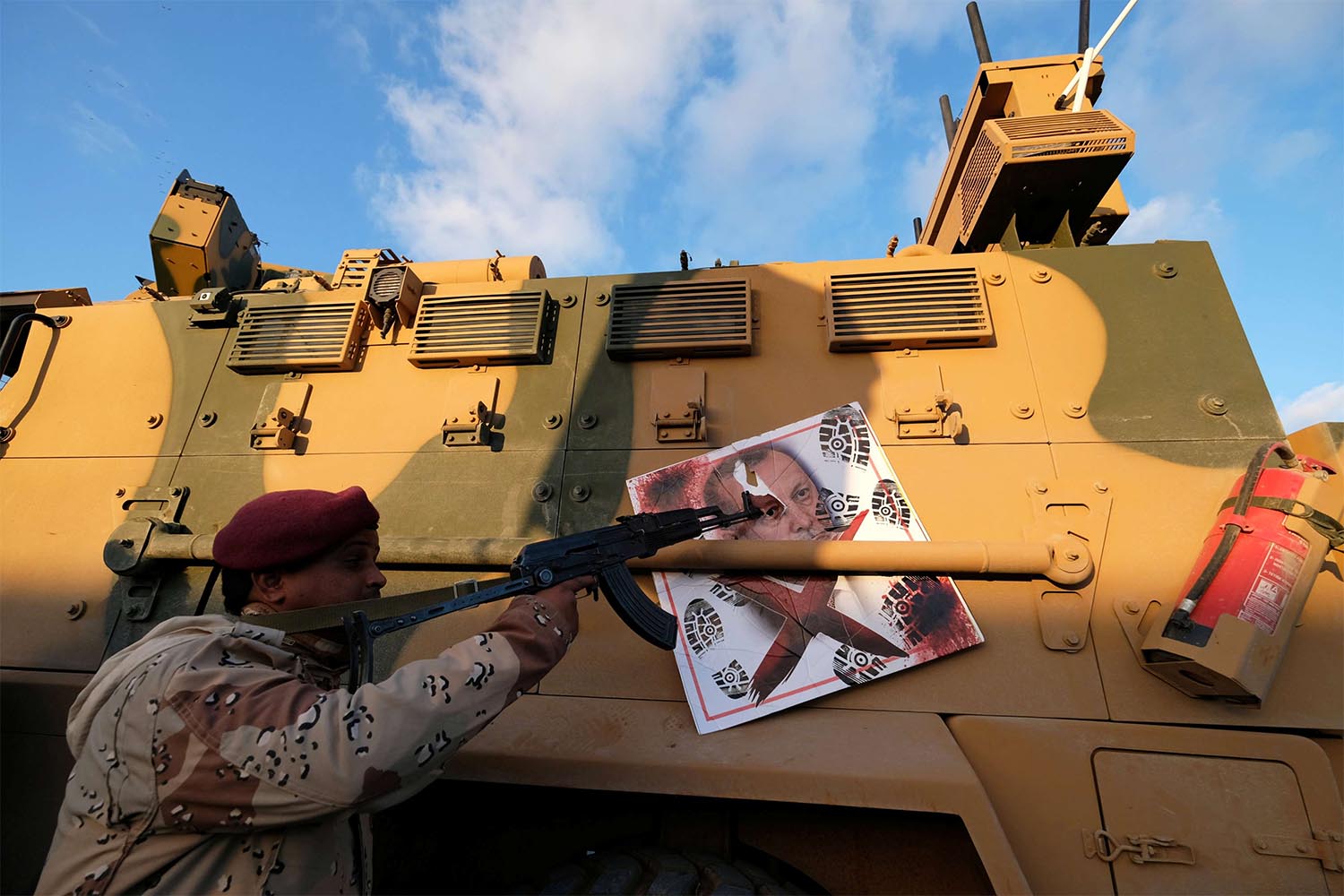 A member of Libyan National Army (LNA) commanded by Khalifa Haftar, points his gun to the image of Turkish President Tayyip Erdogan