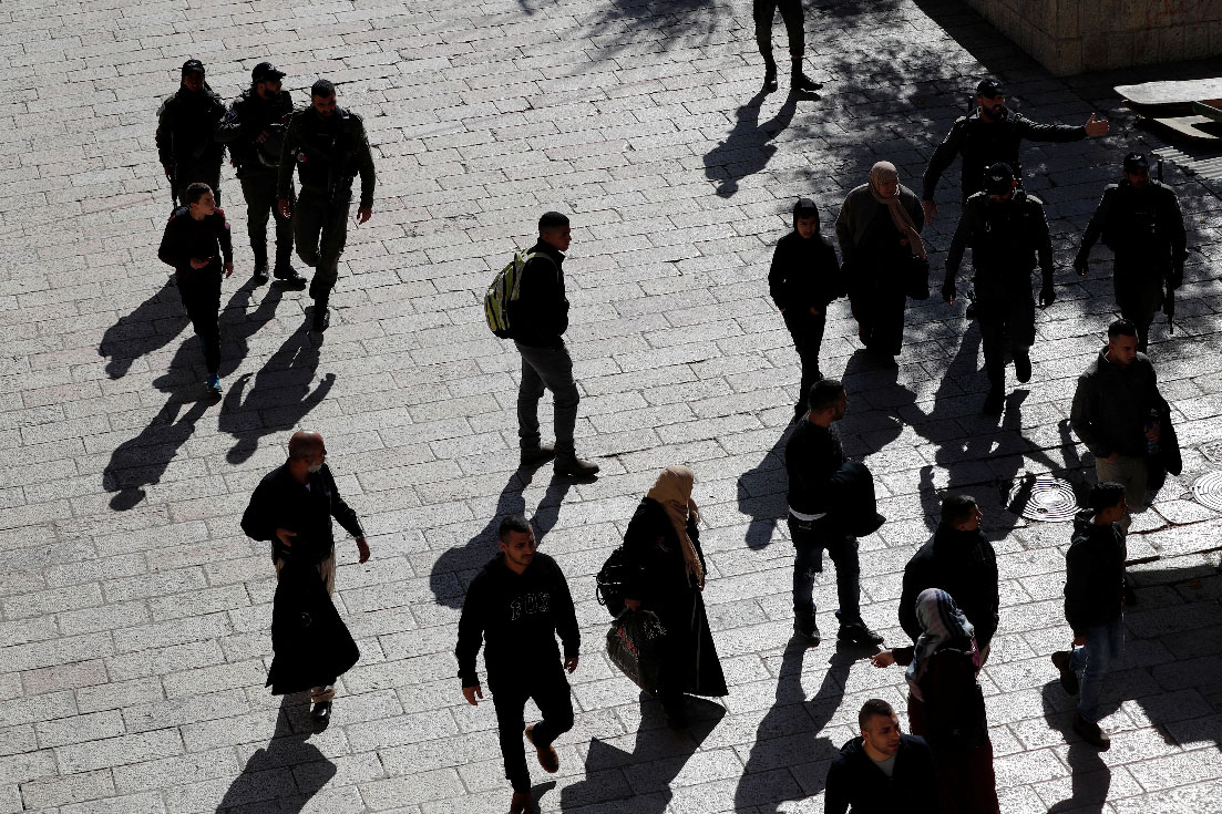 Israeli security personnel gesture to people close to the scene of a suspected shooting attack in occupied East Jerusalem