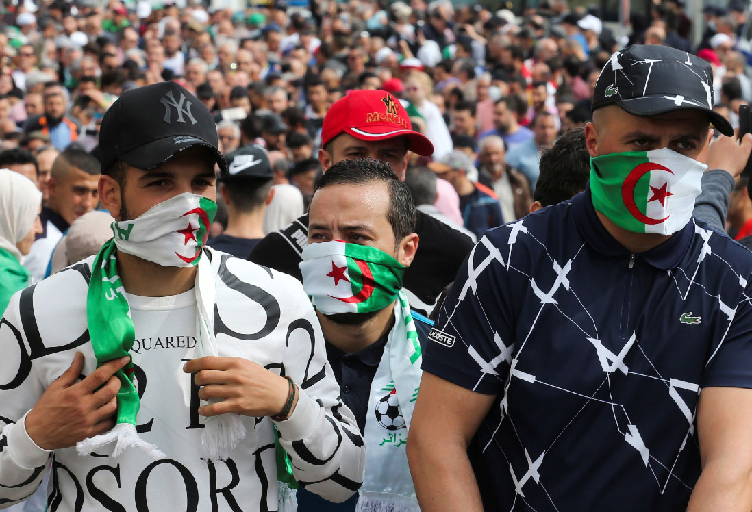 Demonstrators cover their faces with national flags during an anti-government protest in Algiers