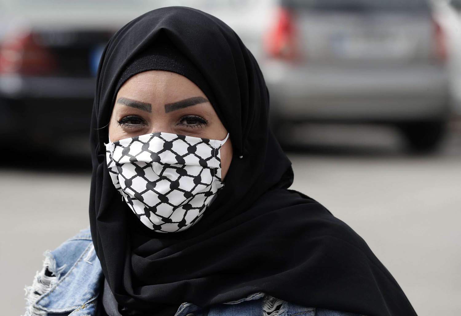 فلسطينية من مخيم برج البراجنة في بيروت ترتدي كمامة على شكل كوفية فلسطينية