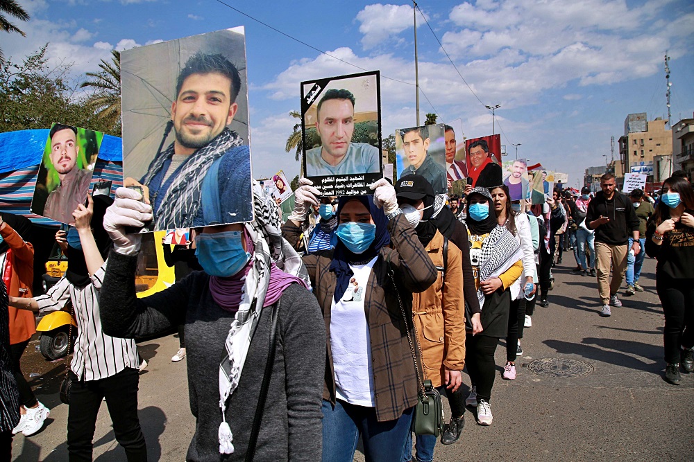 متظاهرون عراقيون يرفعون صور ضحايا العنف