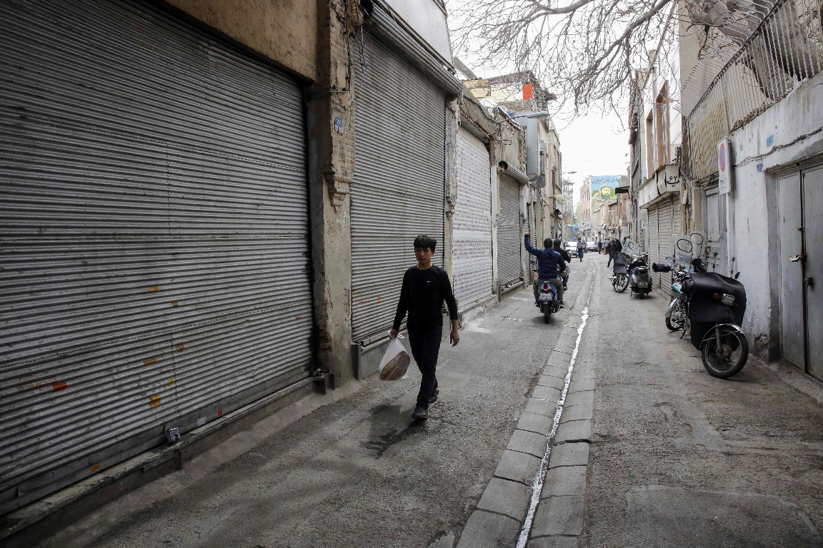 An Iranian youth walks past closed shops in Tehran's grand bazaar