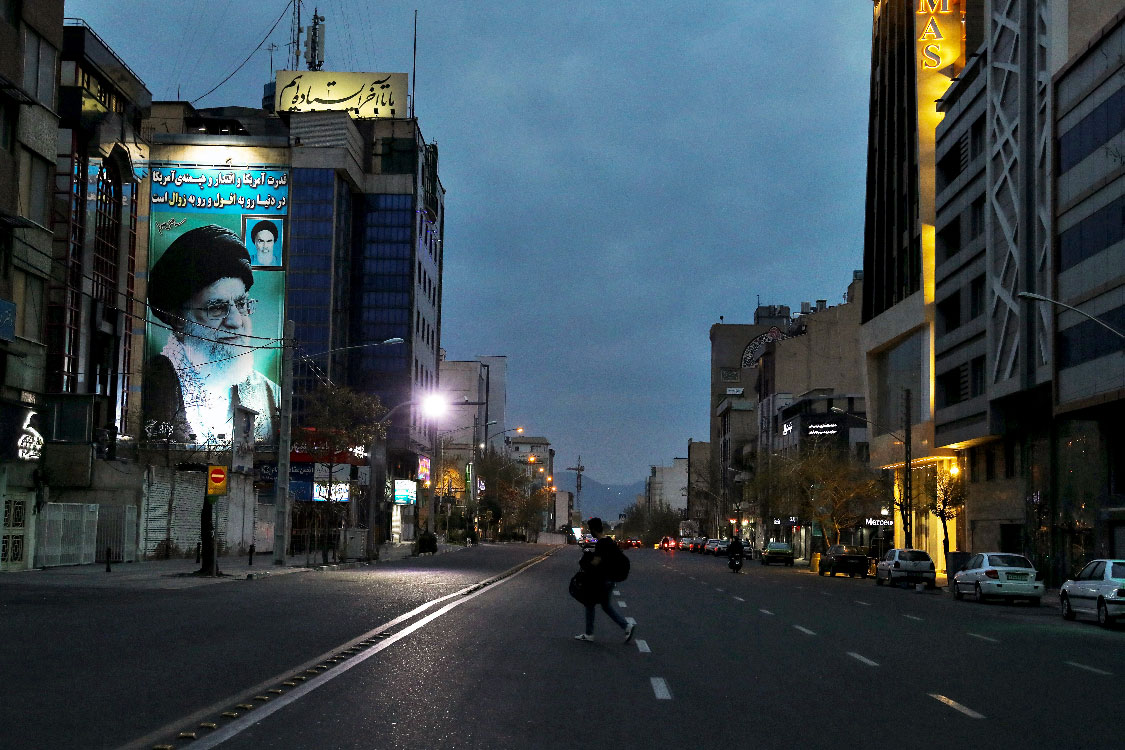 A pedestrian crosses an empty street in Tehran