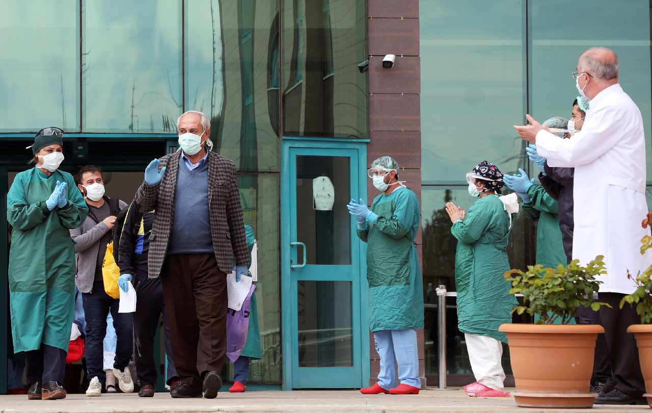 Medical staff members applaud patients who have recovered from COVID-19