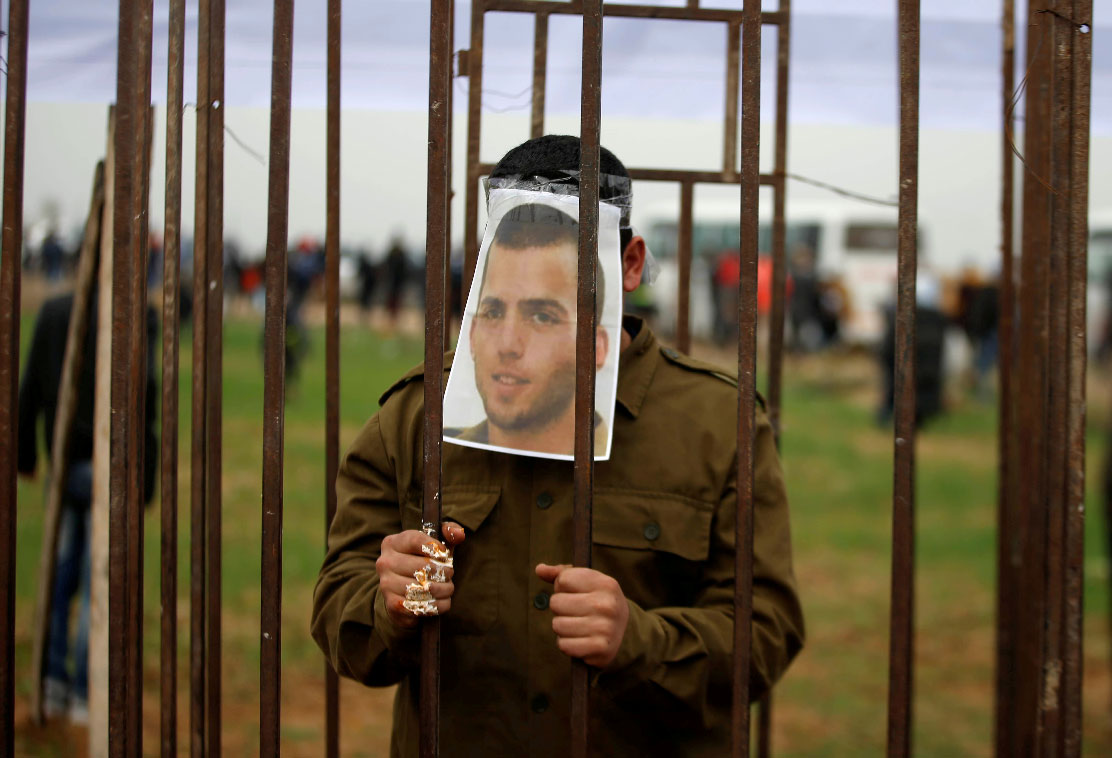 A Palestinian man playing the role of Israeli soldier Oron Shaul stands in a mock jail during a rally in solidarity with Palestinian prisoners