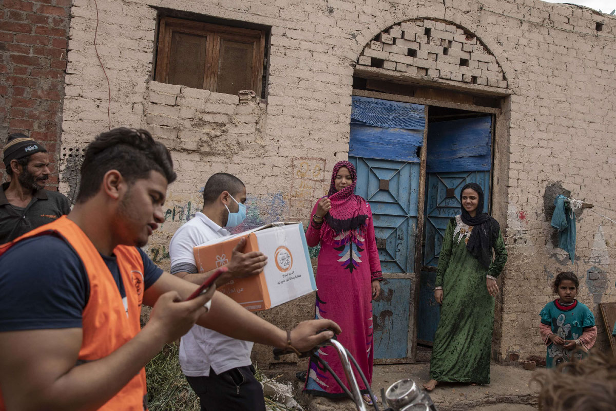 NGO workers distribute cartons filled with food to people in Cairo, Egypt