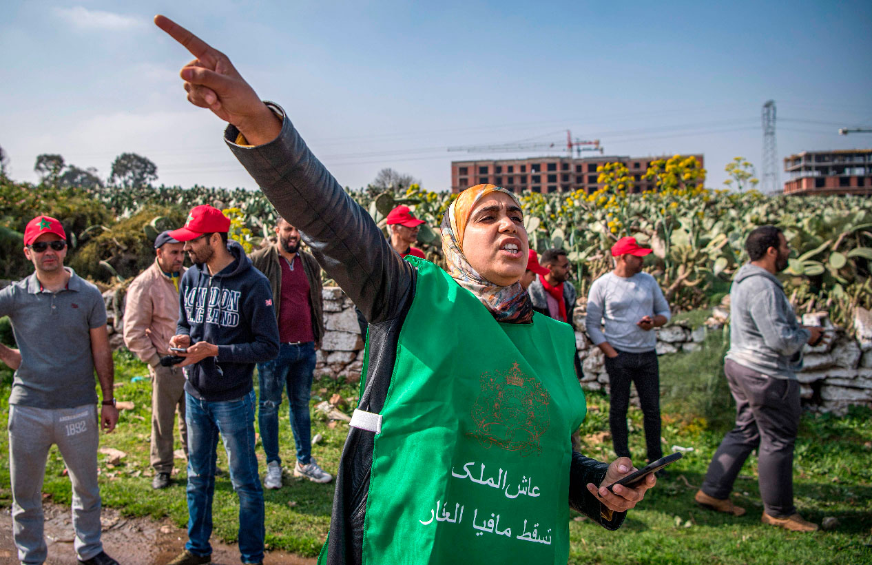 A woman wearing a vest with the slogan "long live the King, down with the real estate mafia", chants slogans during a demonstration against the "Bab Darna" real estate group in Casablanca