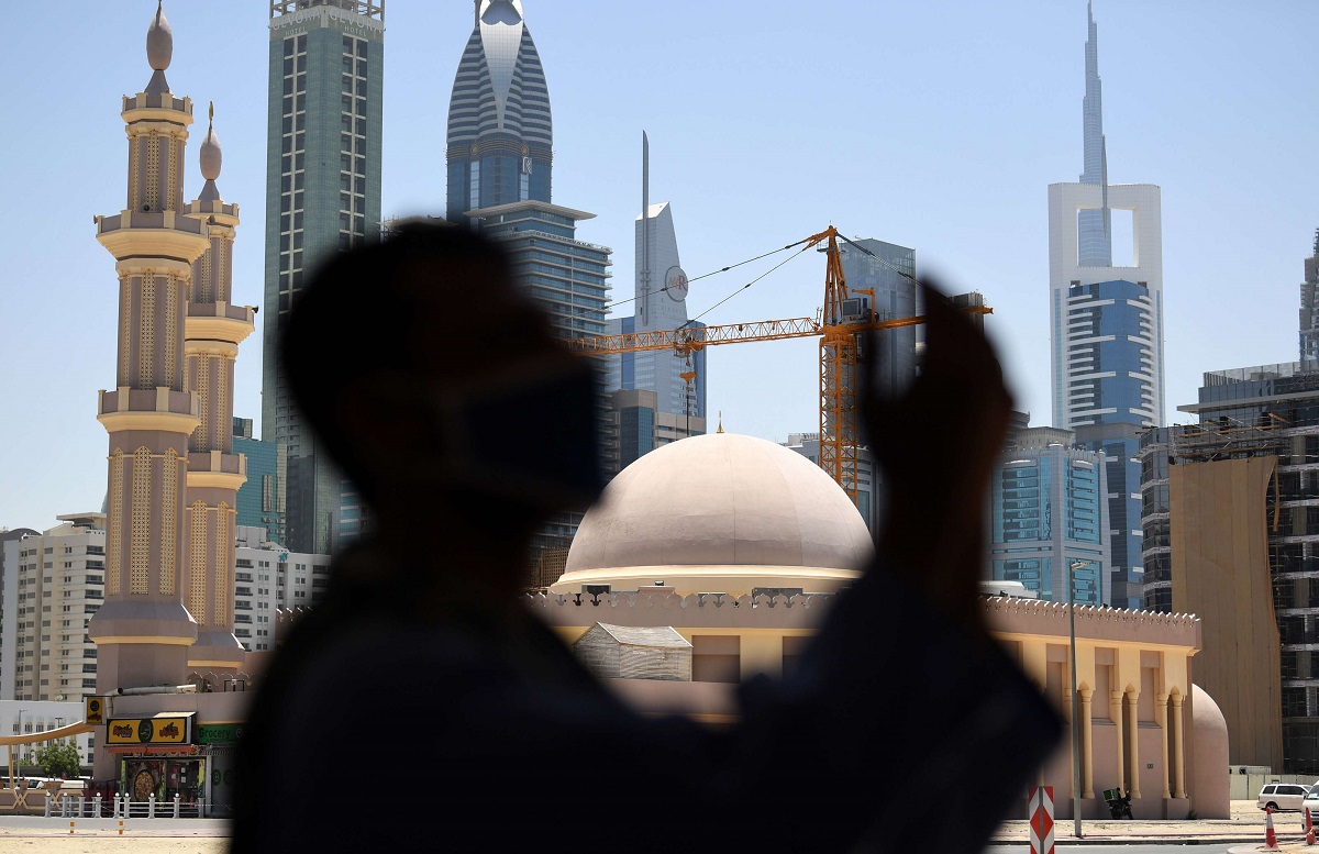 رجل يلبس كمامة يصلي بالقرب من مسجد بدبي في رمضان وسط حظر تجول بسبب كورونا