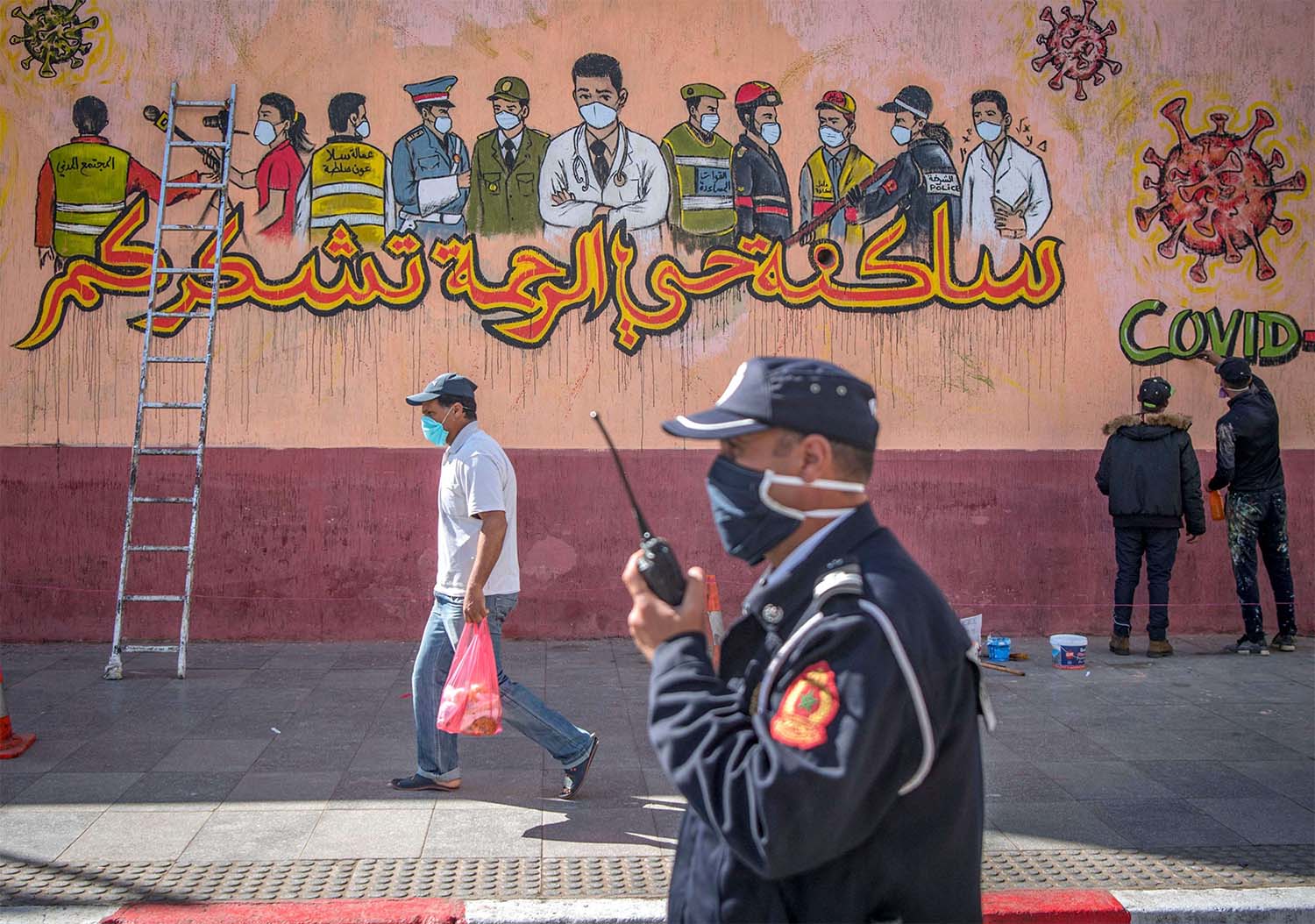  Policeman walks past artists working on a mural thanking essential workers amid the COVID-19 pandemic in Sale