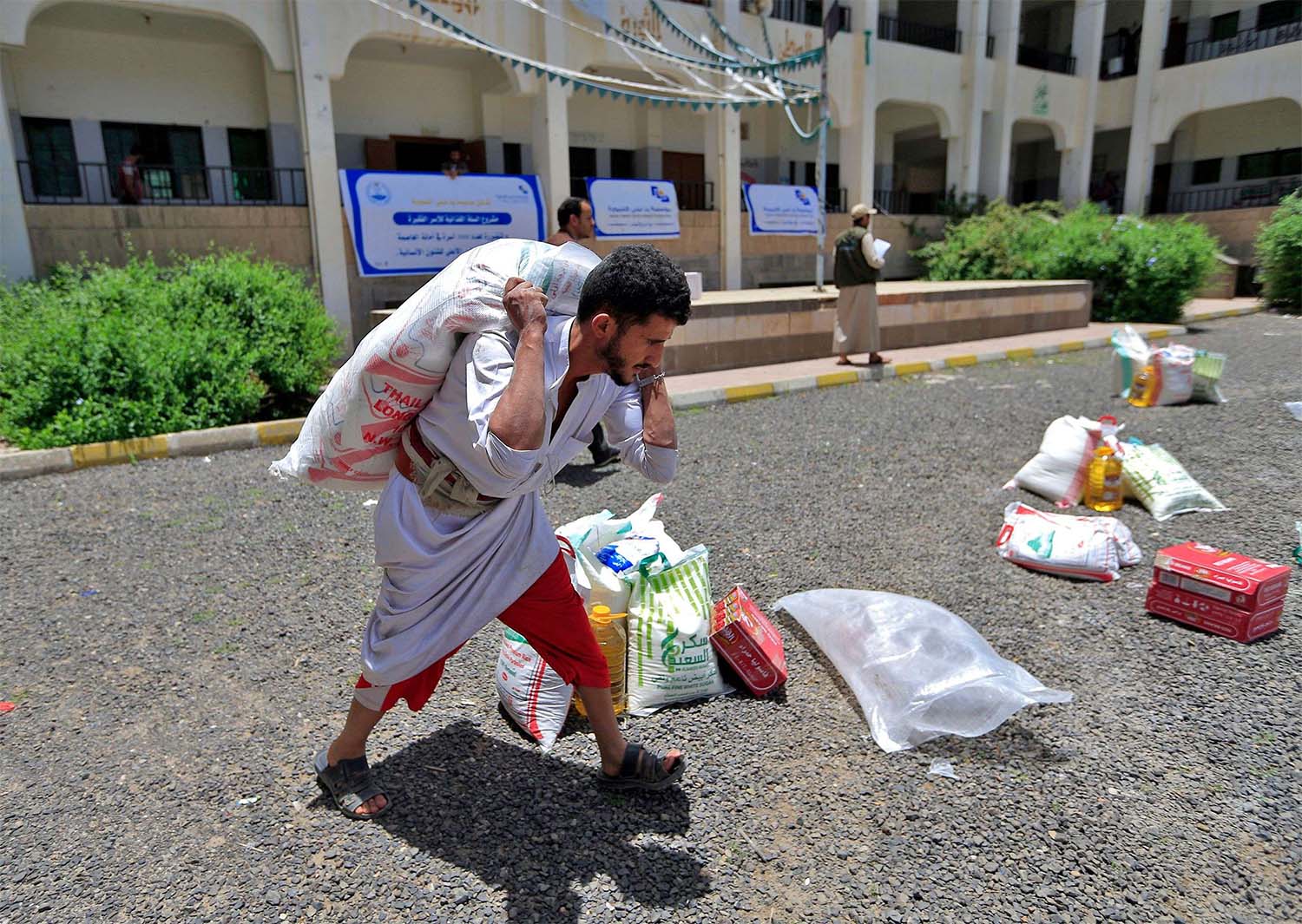 A Yemeni man carries a portion of food aid in Sanaa