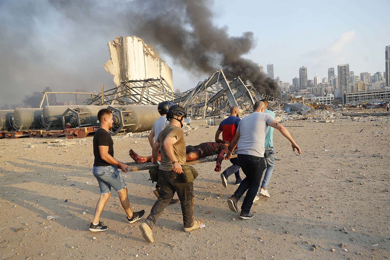 Civilians carry a person at the explosion scene that hit the seaport, in Beirut 