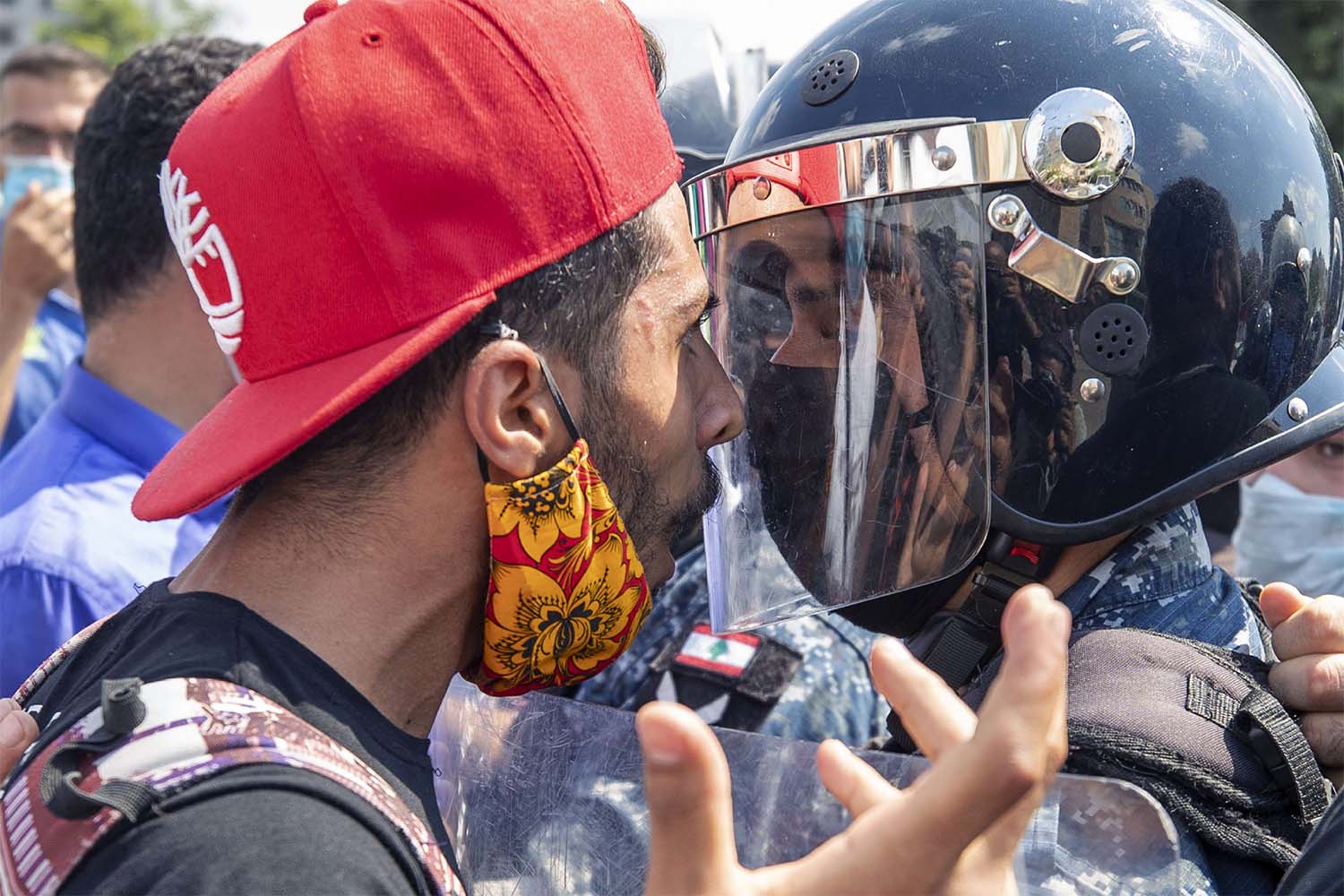 An anti-government protester faces riot police outside the Ministry of Energy and Water in Beirut