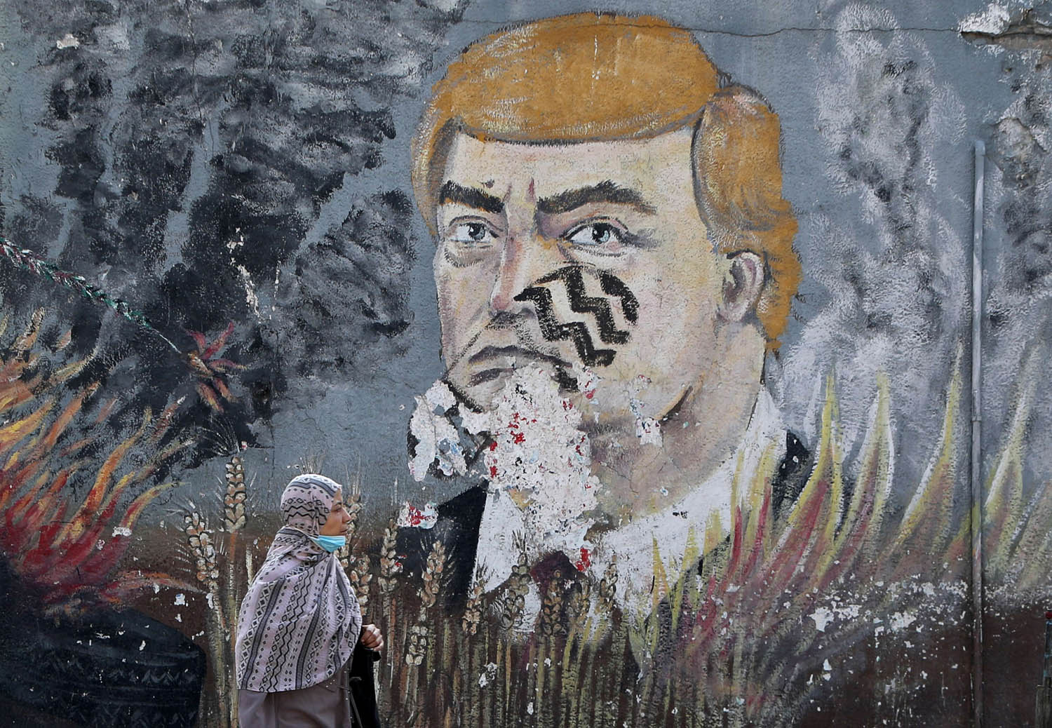 فلسطينية تمر بجانب صورة لترامب مرسومة على جدار في غزة