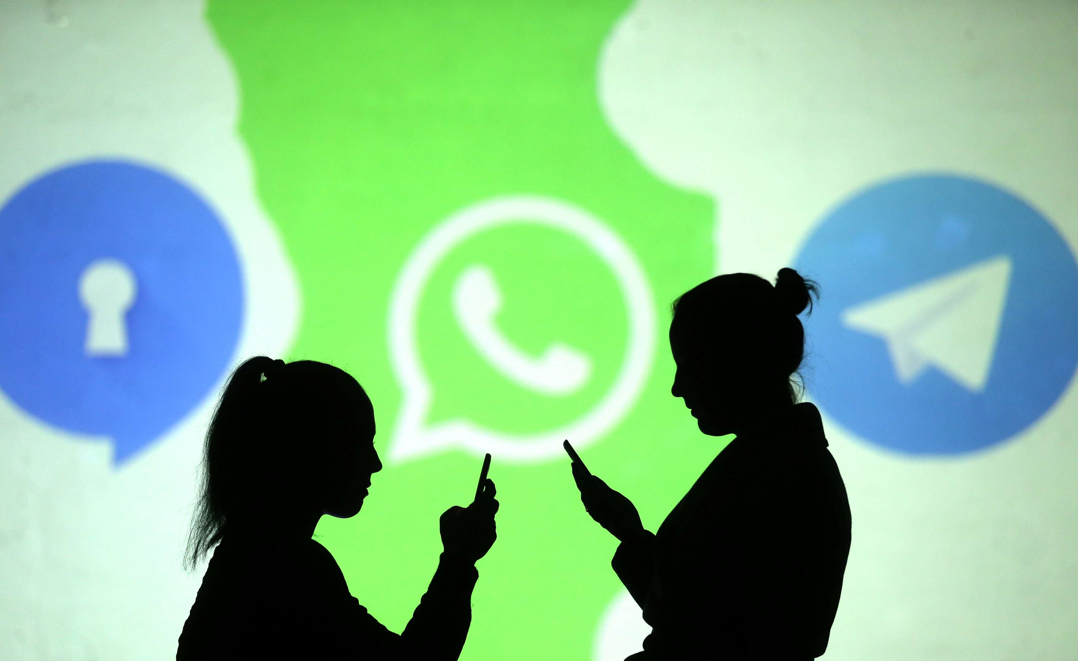 صور ظلية لمستخدمي هواتف محمولة تظهر بجوار شعارات تطبيقات واتساب وتليغرام وسيغنال
