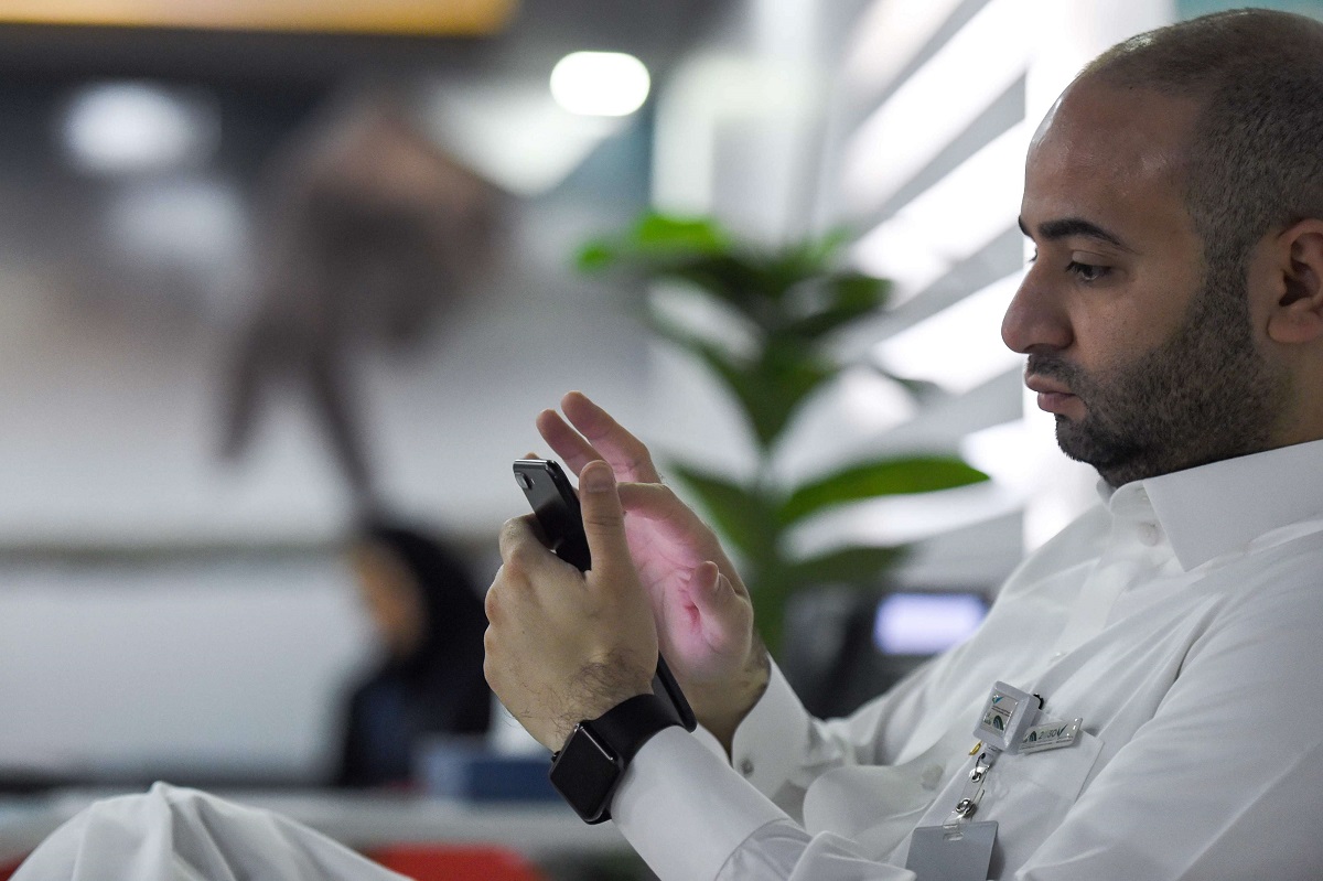 موظف سعودي يتفقد هاتفه المحمول في مكتبه بالعاصمة الرياض