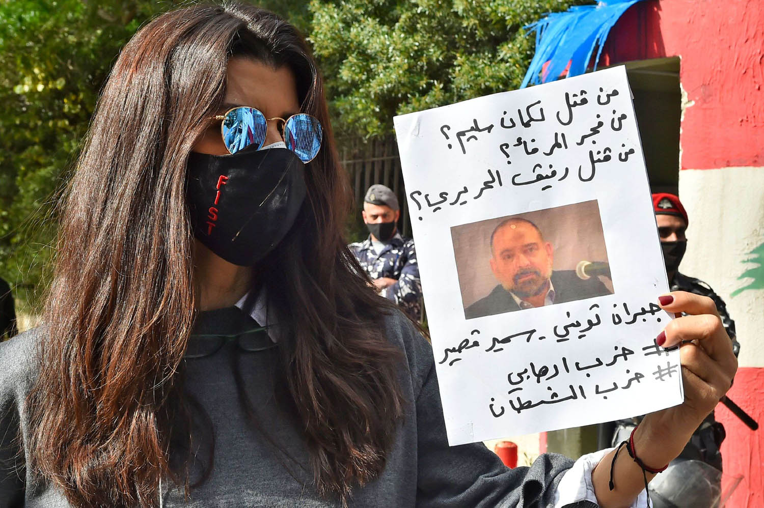 متظاهرة لبنانية ترفع صورة لقمان سليم وتتهم حزب الله بقتله