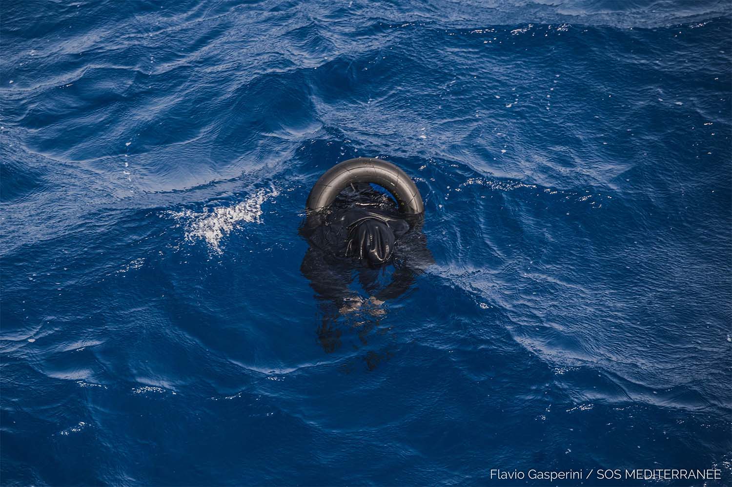 A dead migrant floats on the sea after his boat capsized off Libyan coast