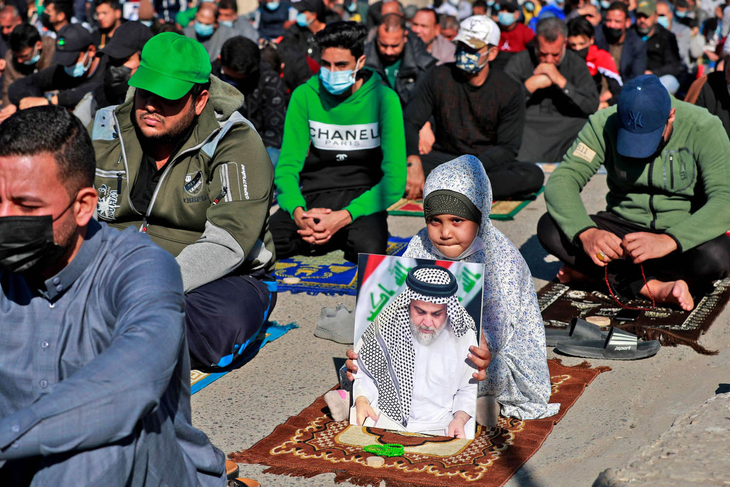 طفلة تحمل صورة الصدر اثناء الصلاة في بغداد