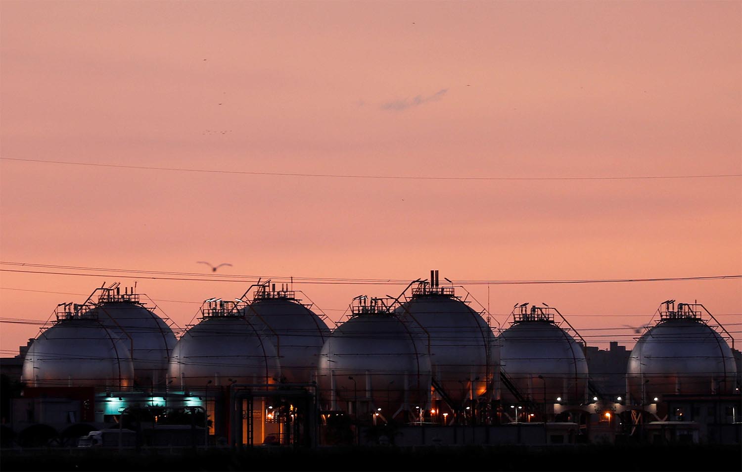 A plant's gas tanks are seen during sunset along a highway of Alexandria
