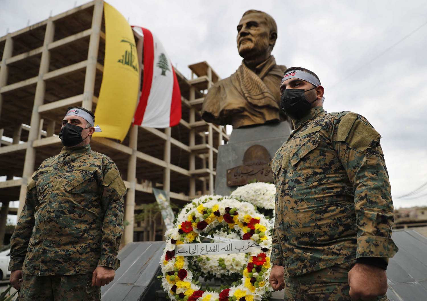 مقاتلون من حزب الله أمام  تمثال لقائد فيلق القدس الراحل قاسم سليماني