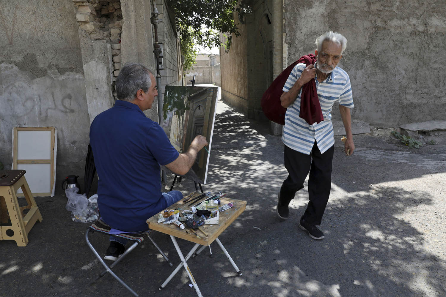 Painter Hassan Naderali paints an old building in the historic neighborhood of Oudlajan, in Tehran