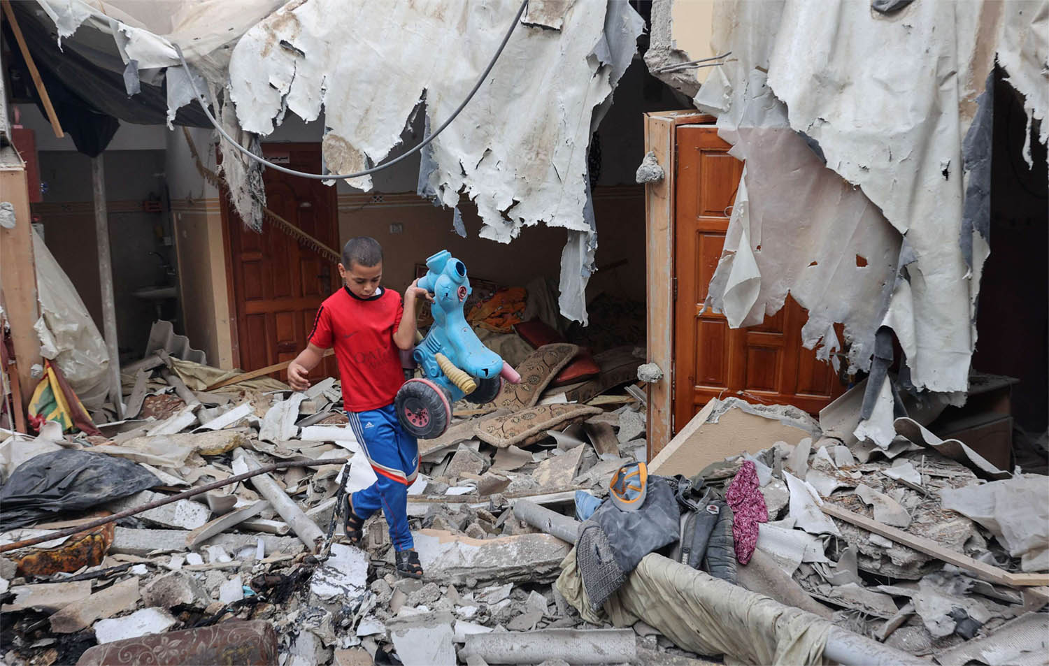 Palestinian boy salvaging a toy from the rubble of his house