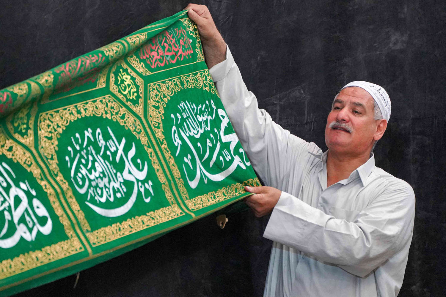 عراقي يرفع راية تحمل اسم الرسول محمد وعائلته علي وفاطمة