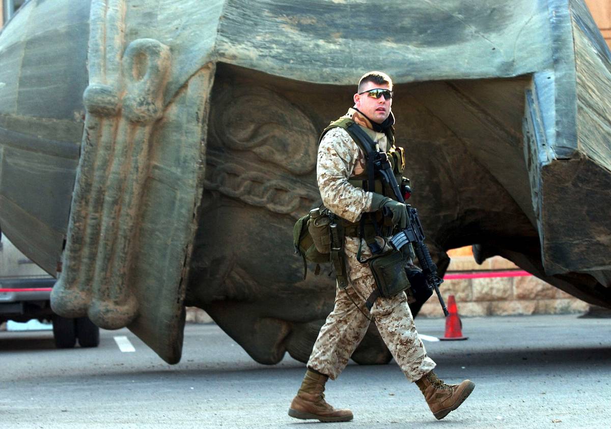 جندي أميركي يمر بالقرب من تمثال محطم لصدام حسين (2003)