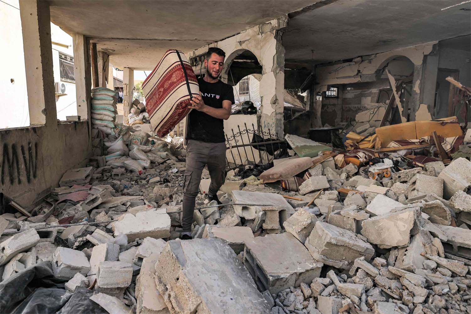 A man walks with a cushion through rubble in a destroyed flat in a building in Jenin