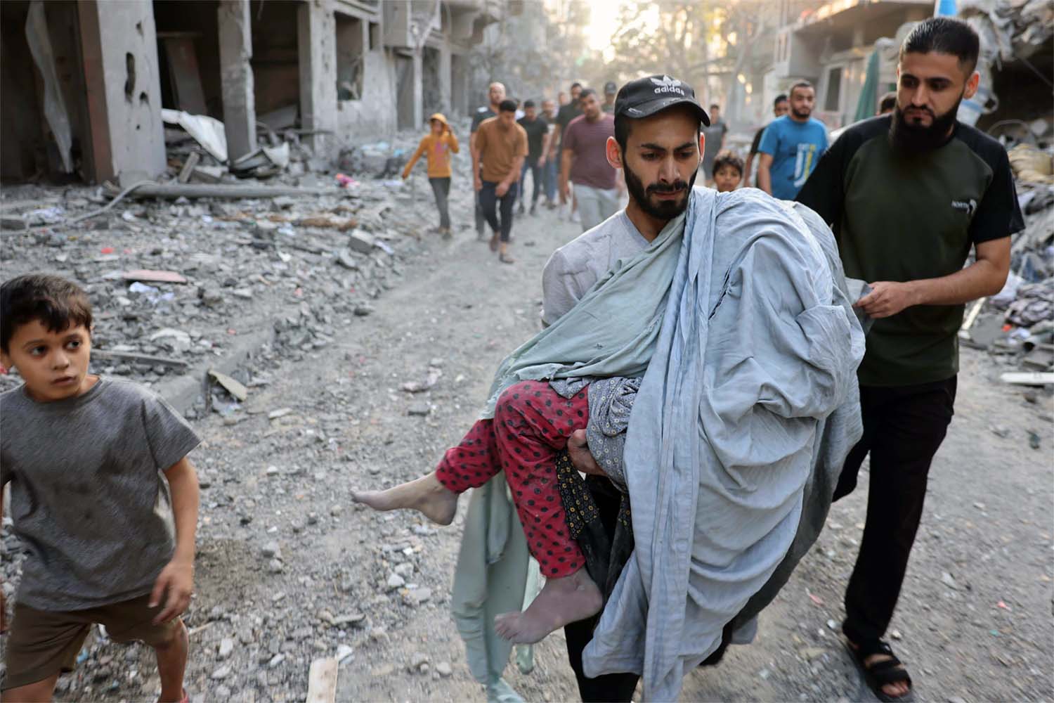 A Palestinian man carries the covered body of a girl removed from the rubble of a building in central Gaza