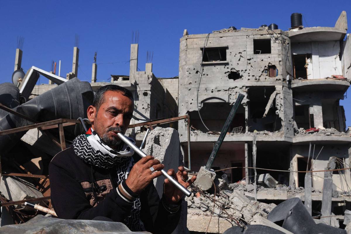 فلسطيني يعزف الناي بجوار اطلال مبان مدمرة بالقصف الإسرائيلي