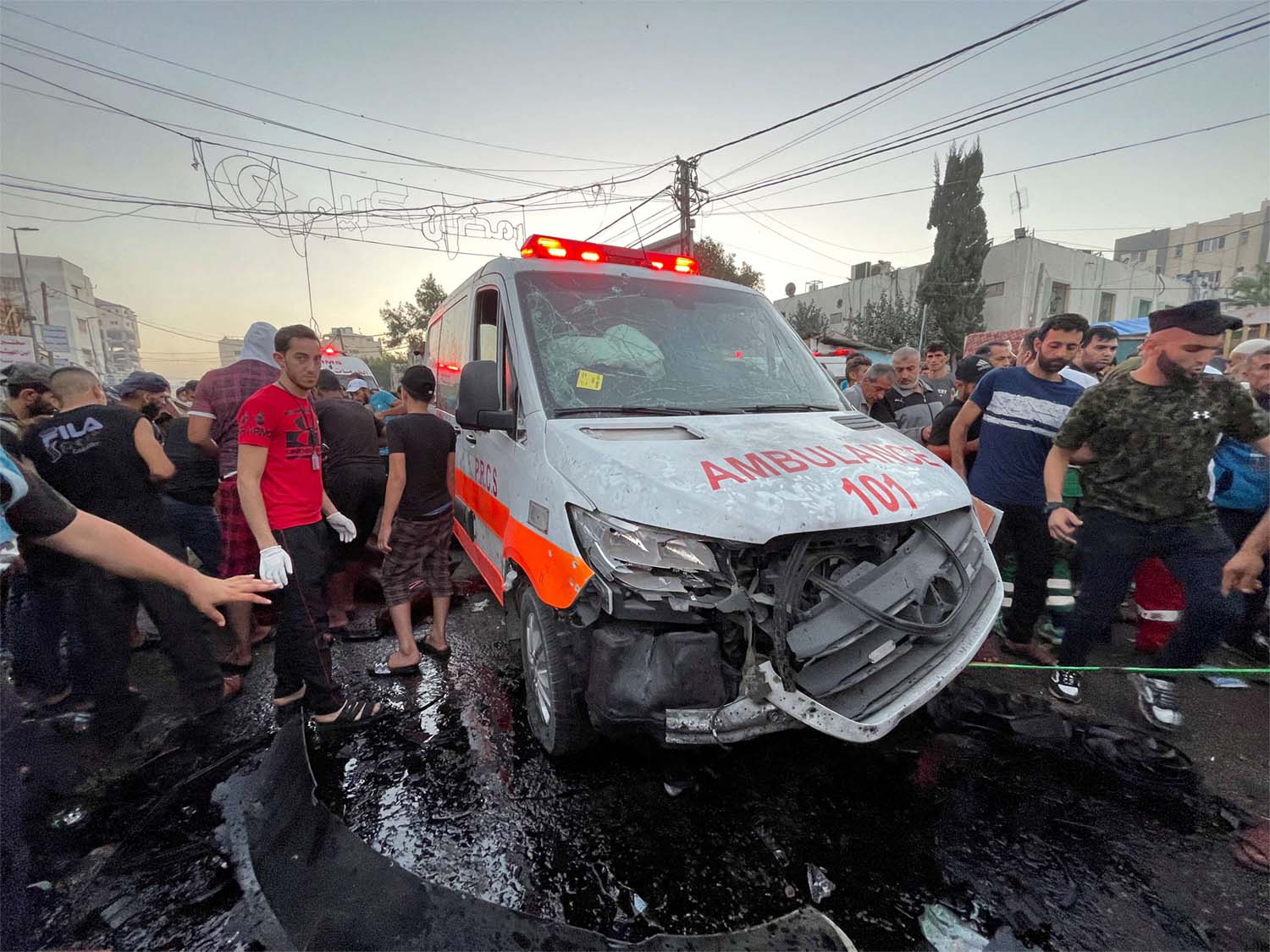Palestinians check the damages after a convoy of ambulances was hit, at the entrance of Shifa hospital in Gaza City