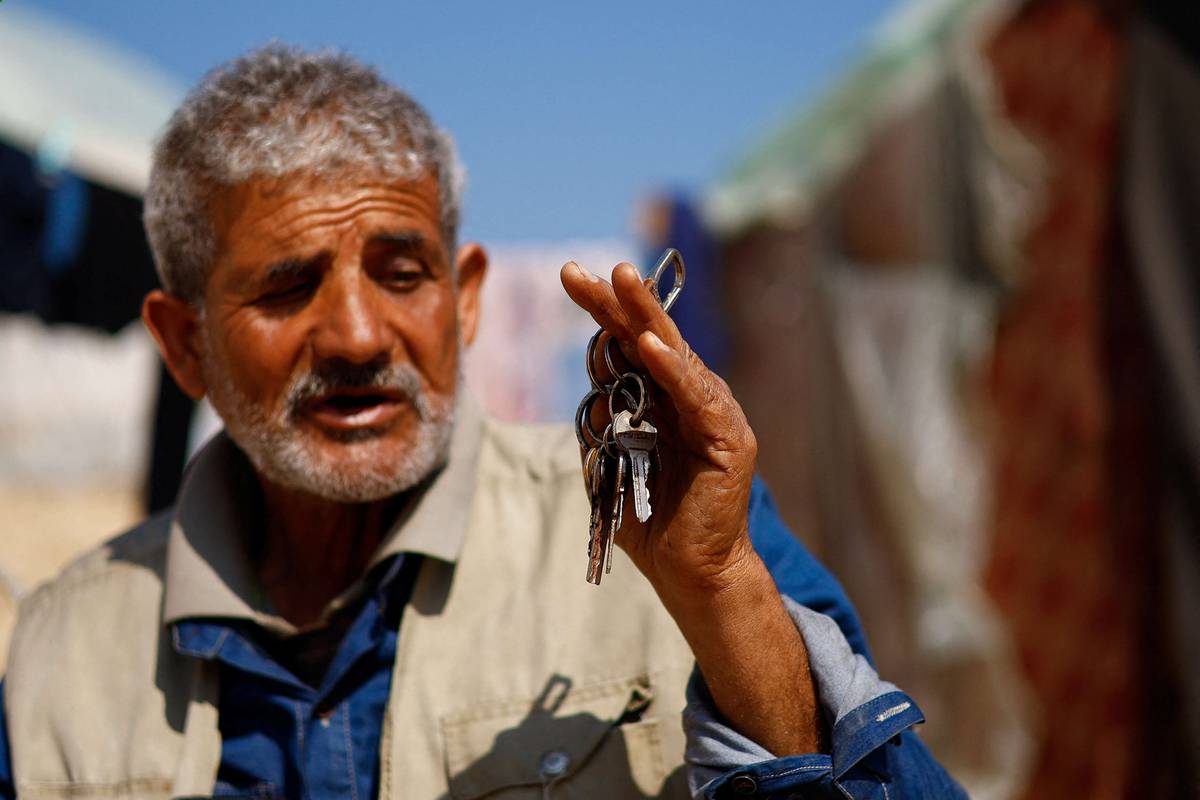 فلسطيني يعرض مفاتيح بيته المدمر في غزة
